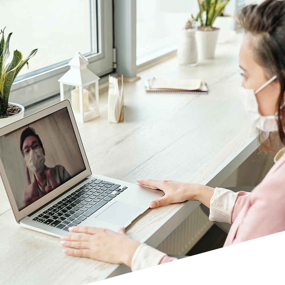 Lady with a mask, talking to someone via a laptop video call