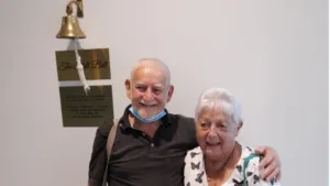 a man and a woman standing next to a bell.